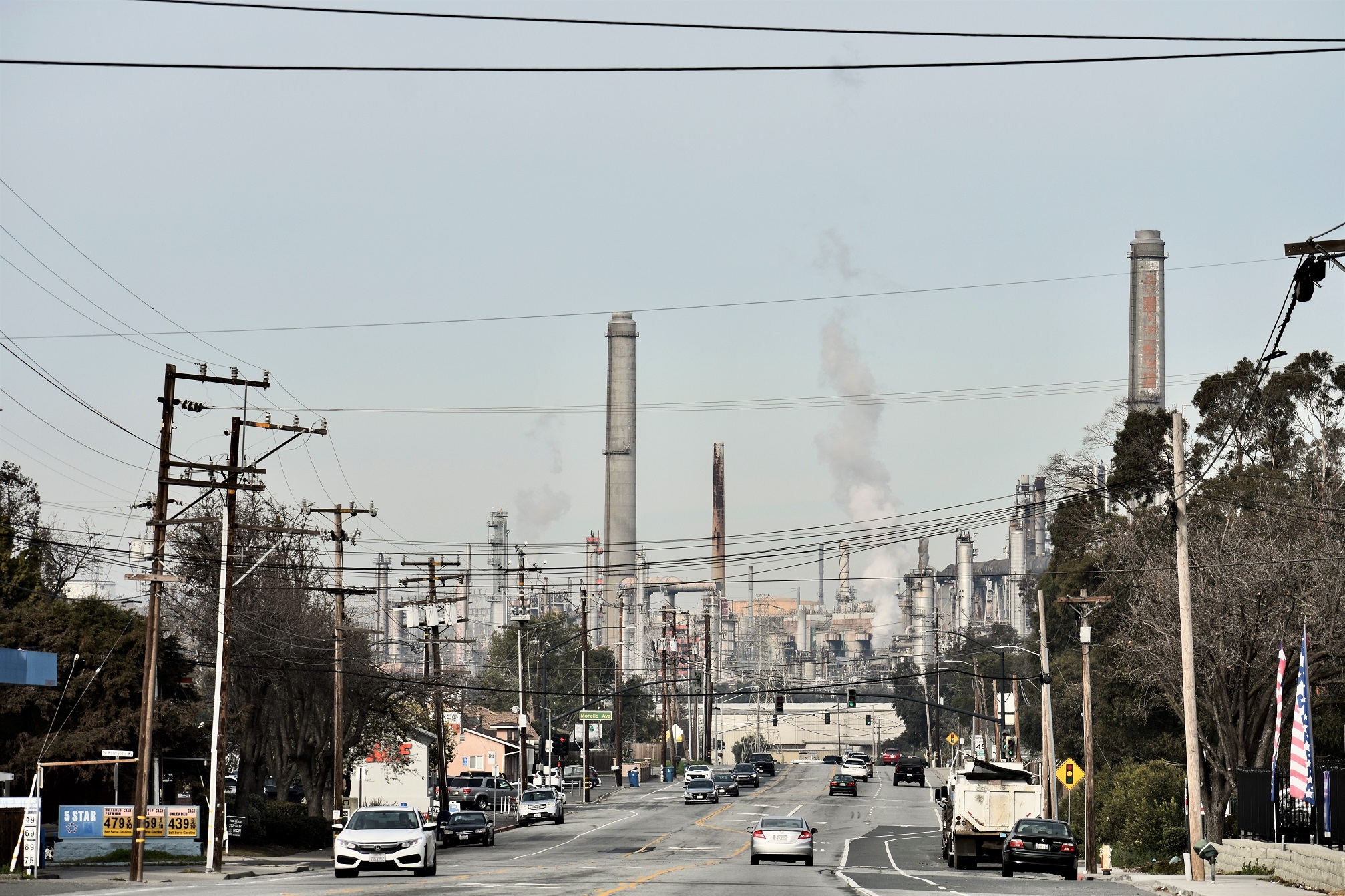 Refinery smokestacks at end of busy street