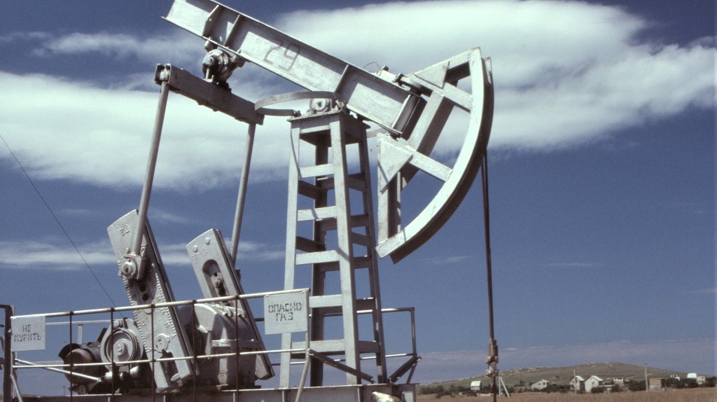 Oil-drilling pumpjack in front of homes