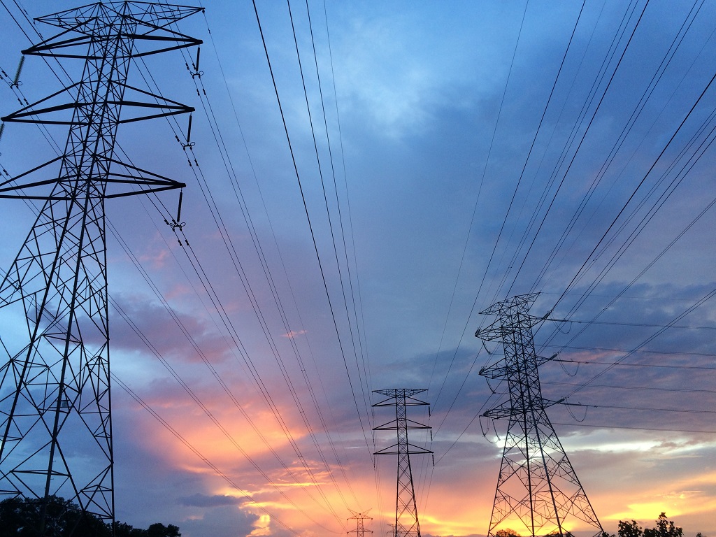 Transmission towers under blue-gray sky with orange and yellow highlights