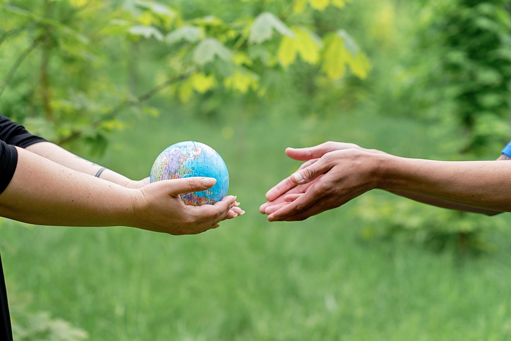 Hands passing a globe of the earth into other hands