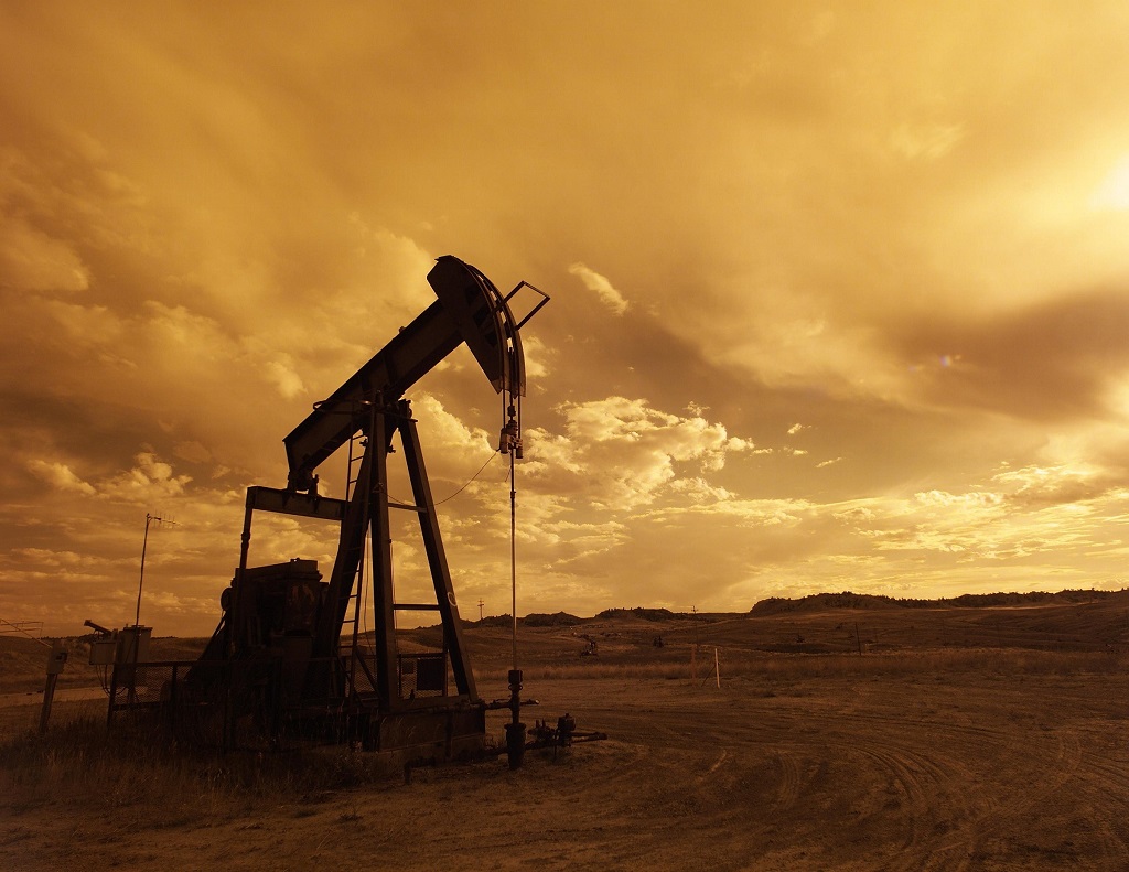 Pump jack silhouetted against yellow sky
