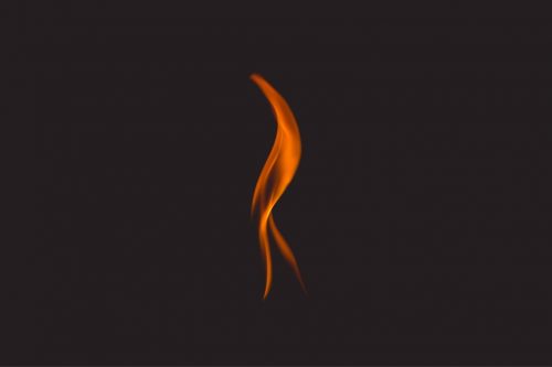 Slender orange fiery flame on black ground