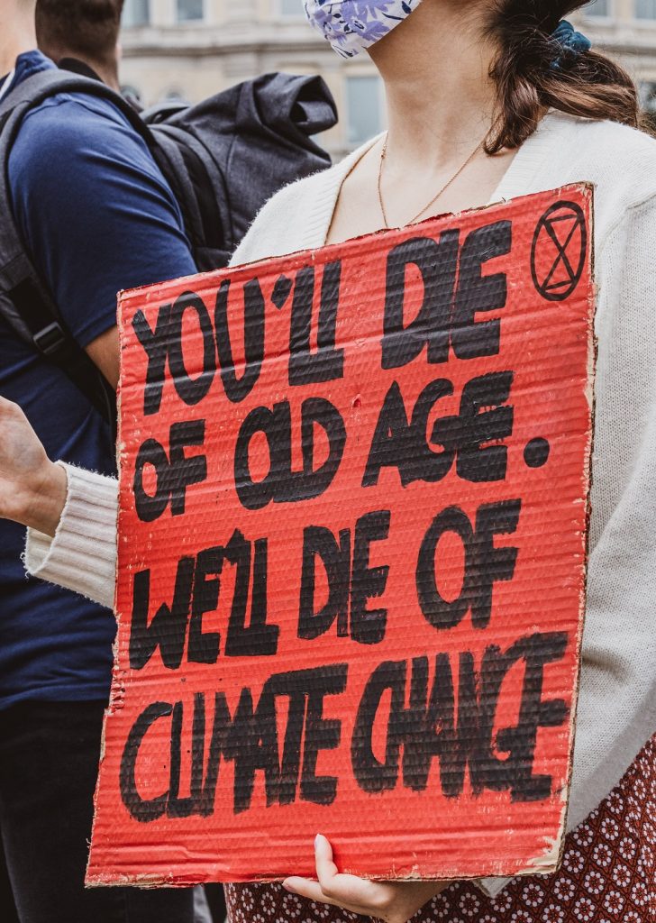 Young woman holding sign that says "You'll die of old age. We'll die of climate change."
