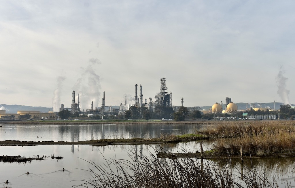Long view of an oil refinery sitting adjacent to wetlands