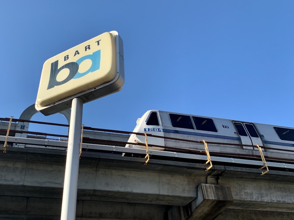 Connect Bay Area ballot measure A BART train passes approaches a BART sign as it passes on an overhead rail Image credit: 350 Contra Costa Action Volunteer Staff Photo