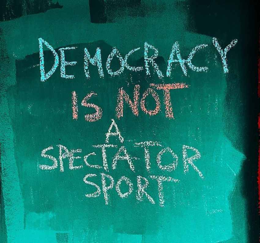 October 2026 Newsletter | 350 Contra Costa Action | "Democracy is not a spectator sport" in colored chalks on shaded green and black background | Image credit: Jon Tyson on Unsplash October 2026 Newsletter| 350 Contra Costa Action Newsletter | 350 Contra Costa Action